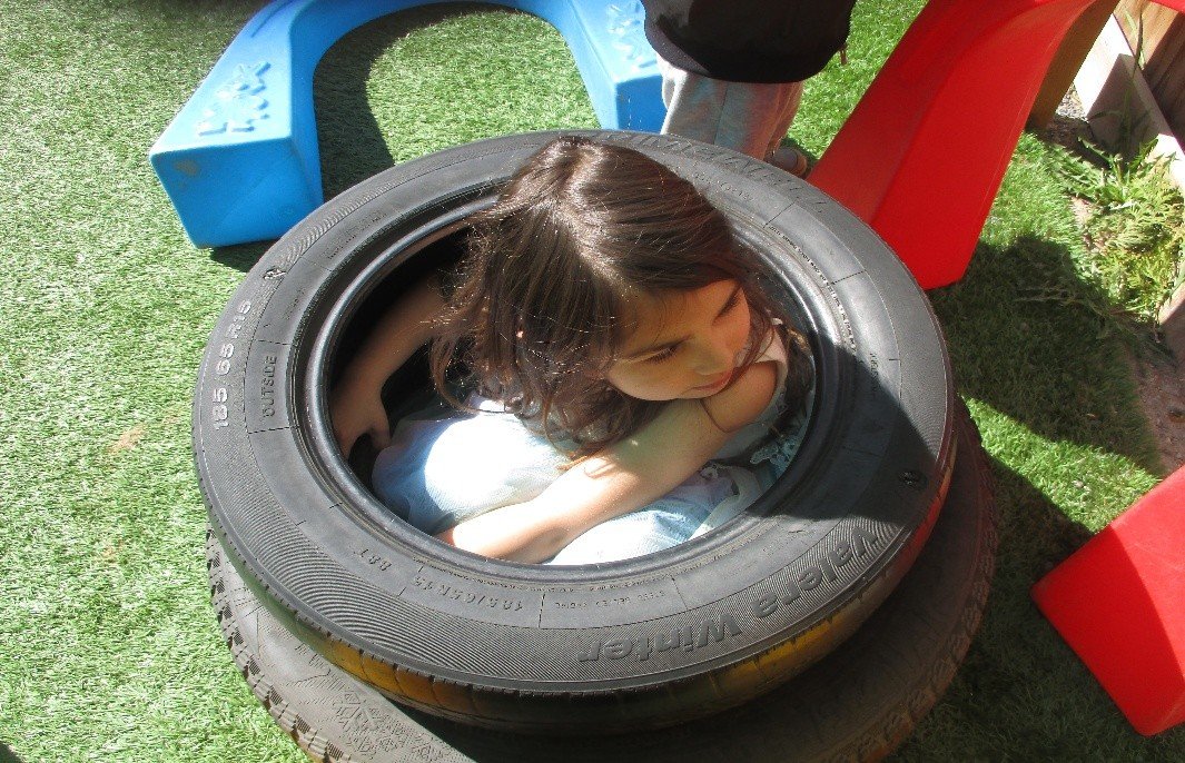 Child exploring inside tyre on artificial grass