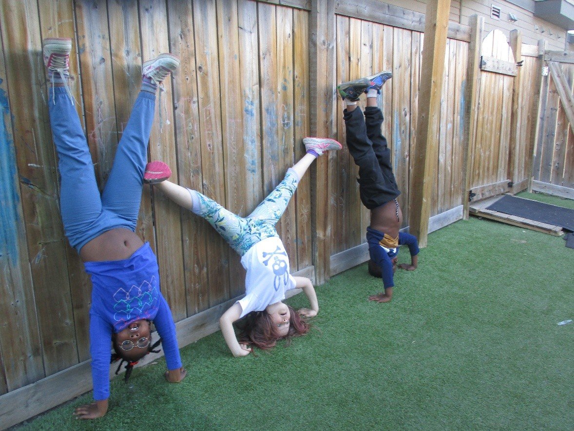 Children doing handstands against the wooden fence