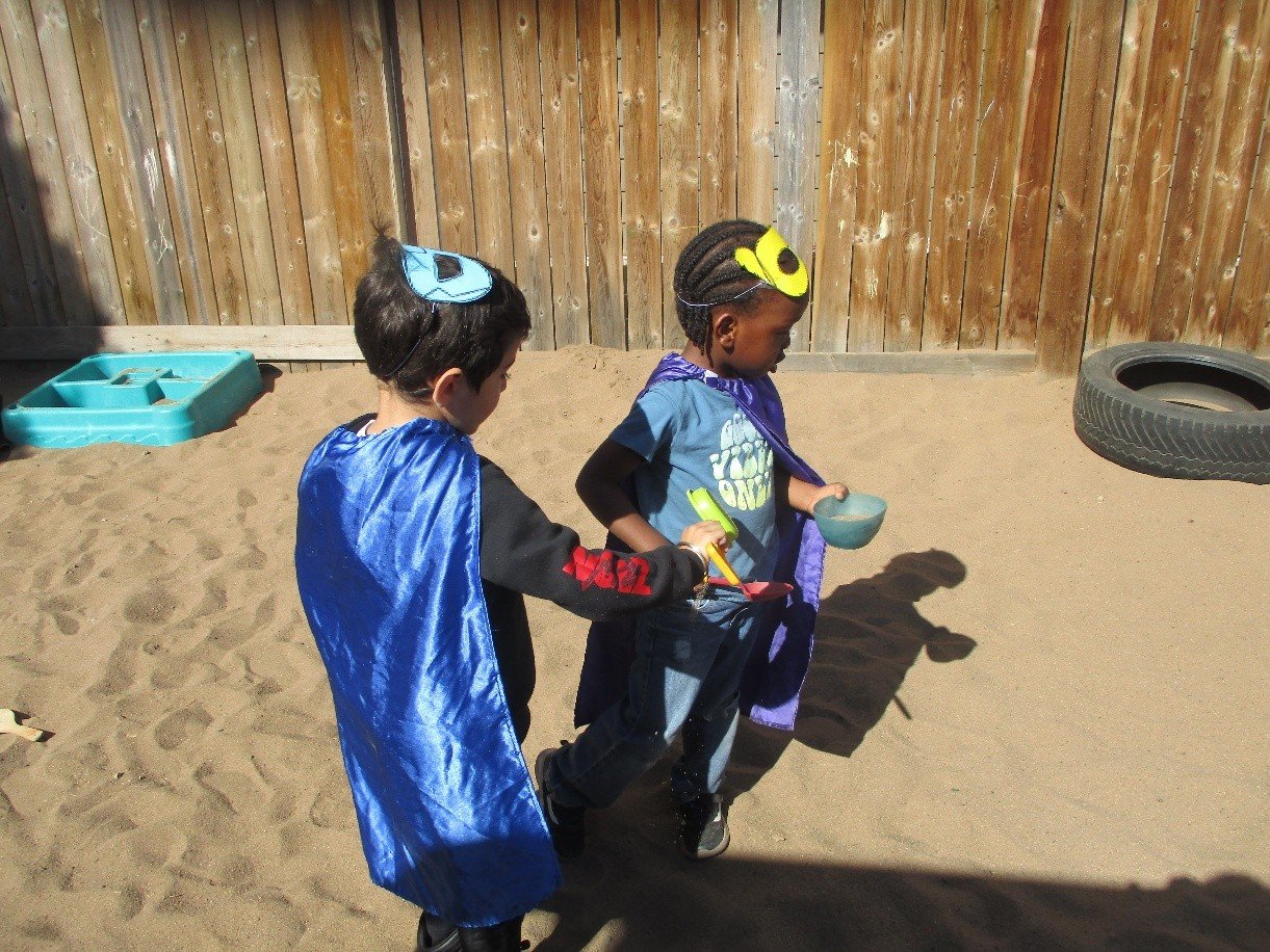 Children playing in superhero costumes in the sandpit